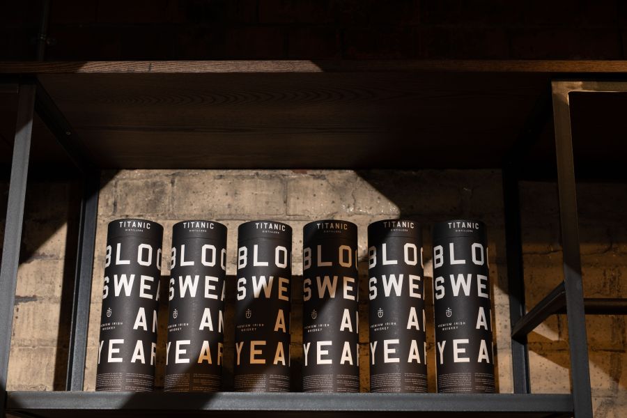 Zes whiskey kokers op een plank van de Titanic Distillers